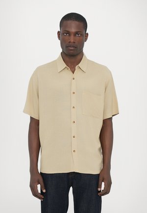 Beige short-sleeve shirt with a straight cut, buttoned front, single chest pocket, and a textured fabric finish.
