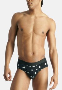 Svarta herrundershorts med vitt Adidas-logomönster, tillverkade av mjukt, elastiskt tyg. Har en bekväm, elastisk midja.