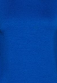 Královsky modrý textil s hladkým, mírně strukturovaným povrchem, vyznačující se rovnoměrnou barvou a hladkým povrchem bez vzorů nebo akcentů.