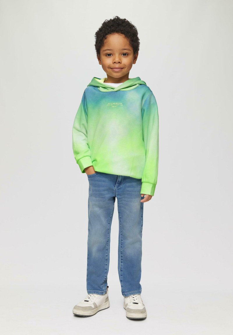 Groene en blauwe gradient hoodie met een voorzak en logo; gecombineerd met lichtblauwe jeans en witte sneakers. Gladde stof en relaxte pasvorm.