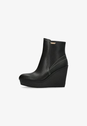 Stivali ankle a tacco wedge neri realizzati in pelle texturizzata, con punta arrotondata, dettagli cuciti sui lati e un sottile logo metallico.