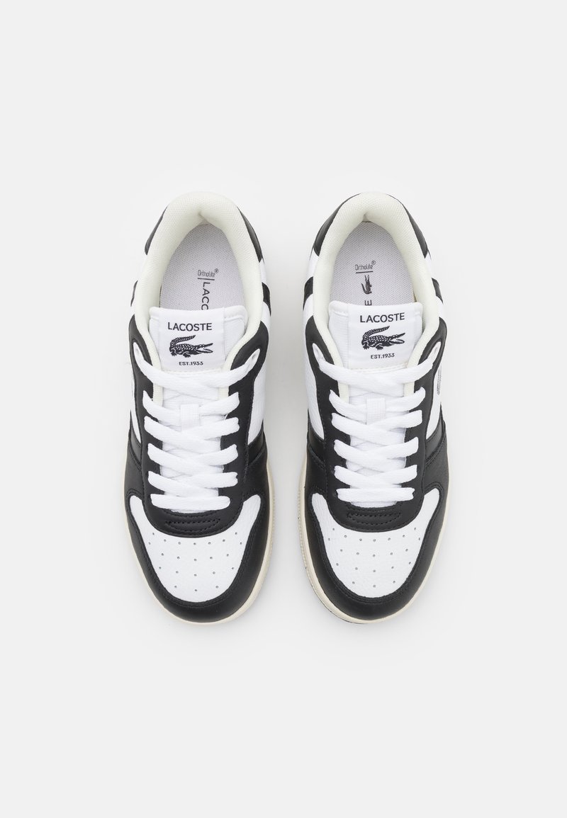 Baskets noires et blanches avec une tige en cuir lisse, bout rond, détails perforés et lacets blancs. Logo Lacoste sur la languette.