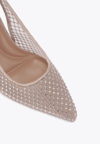 Beżowe szpilki o spiczastym nosku z siateczkowym nałożeniem ozdobionym srebrnymi cyrkoniami, z gładkim wnętrzem i elegancką sylwetką.