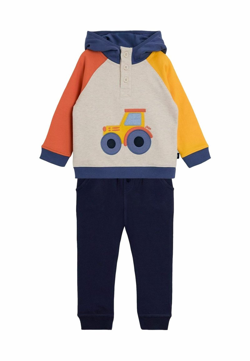 Bunte Kinderkapuzenjacke und Jogginghosen-Set. Kapuzenjacke: grau mit orangefarbenen, gelben und marineblauen Ärmeln; zeigt ein Traktor-Design. Marineblaue Hose.