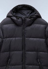 Sort puffjakke med hætte, med et quiltet design, lynlås foran og snøre ved halsen. Glat, blank overflade.