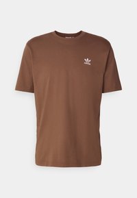 Hnědé bavlněné tričko s krátkým rukávem, kulatým výstřihem a bílým logem Adidas na levé části hrudi. Hladká textura, standardní střih.
