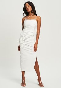 White, fitted midi dress with a square neckline and thin shoulder straps. Features side ruching and a high slit. Smooth texture.