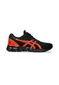 Scarpa sportiva nera con tomaia in rete testurizzata, caratterizzata da accenti rossi e un logo stampato. Suola in gomma nera spessa e flessibile con grip.