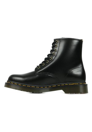 Stivaletto in pelle nera con punta rotonda, cuciture gialle, sei occhielli metallici e una suola robusta. Texture liscia con dettagli minimi.