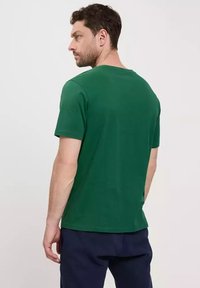 Zielona koszulka krótki rękaw wykonana z miękkiego materiału, z okrągłym dekoltem, standardowym kroju i minimalistycznym designem bez widocznych logo czy wzorów.
