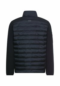 Polstret sort jakke med quiltet front og glatte ærmer i stof. Har en høj krave og et logomærke på bagsiden.