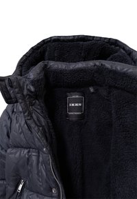 Czarna kurtka puchowa z geometrycznym wzorem na zewnątrz. Miękka czarna polarowa podszewka, zamek błyskawiczny i widoczna metka marki wewnątrz.