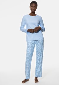 Haut bleu clair à manches longues associé à un pantalon bleu clair à motifs floraux. Tissu doux, coupe décontractée, jambes longue.