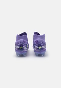 Las botas de fútbol moradas presentan un diseño de tobillo ajustado, suela translúcida y acentos en verde lima. Parte superior texturizada con una silueta elegante.