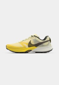 Nike trkačke tenisice u svijetložutoj i sivoj boji, s teksturiranim mrežastim gornjim dijelom, crnim detaljima i gumeni potplat s Vibram brandingom.