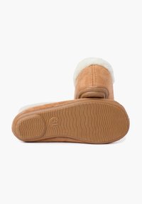 Chaussons en daim beige à enfiler avec une doublure moelleuse blanche et une semelle en caoutchouc texturée avec un motif en vagues. Taille indiquée comme 31.