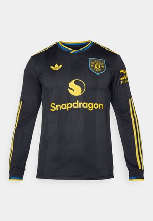 Svart langermet fotballdrakt med gule detaljer. Har snapdragon-logo og klubbmerke. Stripete skuldre og teksturert stoff.
