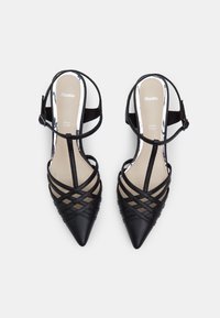 Juodos smailianos kojinėms slingback bateliai su kryžminėmis diržais, lygiu paviršiumi ir reguliuojamu kulkšnies dirželiu. Viduje yra neutralus padas.