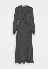 Svart prickig omlotklänning med långa ärmar, rynkad halsringning och sidoknytning. Mjuk tyg, ankel-lång med en rynkad nederkant.