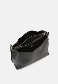 Svart läder tote-väska med en mjuk, strukturerad yta. Har en zippered fack och tryckknappslås. Ren, minimalistisk design.