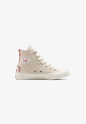 Beige canvas high-top sneaker met rubberen zool. Voorzien van een logopatch, rode accenten en een geborduurd appeldesign op de hiel.