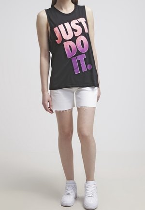 Czarny top bez rękawów z różowym gradientowym napisem "JUST DO IT", połączony z białymi dżinsowymi szortami i białymi sneakersami. Brak wyraźnych wzorów lub akcentów.