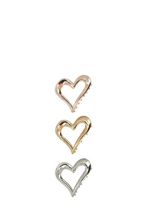 Tre fermagli per capelli a forma di cuore in oro rosa, oro e argento. Ognuno presenta un design aperto con grip testurizzati sul lato inferiore.