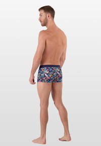 Bunte Badehose mit einem wirbelnden abstrakten Muster, einem dunklen Bund und einer engen Passform, seitlich betrachtet.