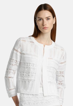 Cardigan bianco lavorato a maglia con motivi intricati, pannelli testurizzati e scollatura rotonda. Ha una apertura frontale e maniche a tre quarti.