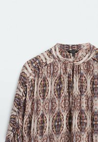 Blouse imprimée à manches longues avec un col montant, motif abstrait coloré dans des tons terreux, et détails plissés près du col.