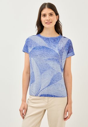 T-shirt bleu clair à manches courtes avec un motif floral texturé et le texte « OWN YOUR VIBE » en blanc. Tissu doux, coupe décontractée.