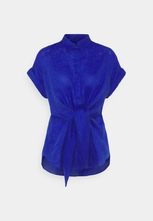 Blauwe linnen blouse met korte opgerolde mouwen, knopsluiting aan de voorkant en een strikdetail in de taille. Gladde textuur en een iets losvallende pasvorm.