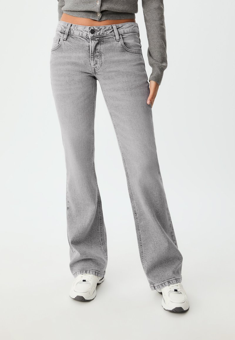 Grå utsvängda jeans med en urblekt finish, med knapp- och dragkedjestängning, framfickor och en avslappnad passform vid nederkanten.