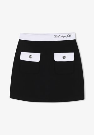 Sort miniskjørt med hvitt midjebånd, med to hvite klafflommer, hver med en metallknapp, og brodert merke på midjebåndet.