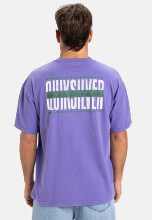 Purple cotton T-shirt featuring large "QUIKSILVER" text in white with green accents and triangular patterns on the back. Soft texture, relaxed fit.