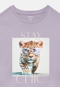 Λεοπάρδαλη με γυαλιά ηλίου σε σχήμα καρδιάς, φοράει μωβ μπλουζάκι με το κείμενο "ΜΕΙΝΕ ΚΟΜΨΟΣ".