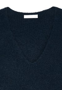 Dark navy sweater with a V-neck design. Knit texture, soft finish, and a tag labeled "NA-KD" visible at the neckline.