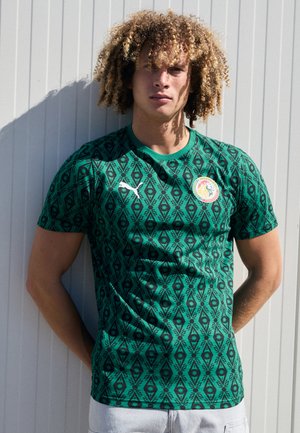 Green short-sleeve jersey with intricate black diamond and leaf patterns, featuring a round collar and a logo on the front.