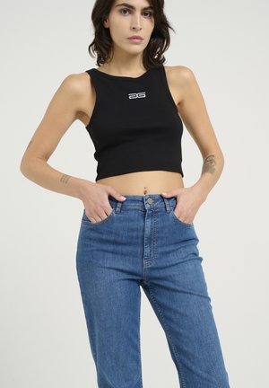 Black ribbed crop top with a round neckline and white logo. Paired with high-waisted blue jeans. Smooth texture and fitted design.