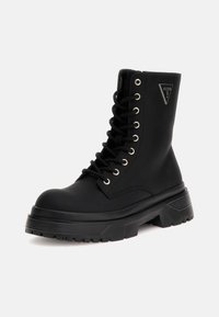 Zwarte enkellaars met vetersluiting, rubberen zool en chunky hak. Voorzien van metalen oogjes en logo-accenten op de zijkant. Gladde textuur.