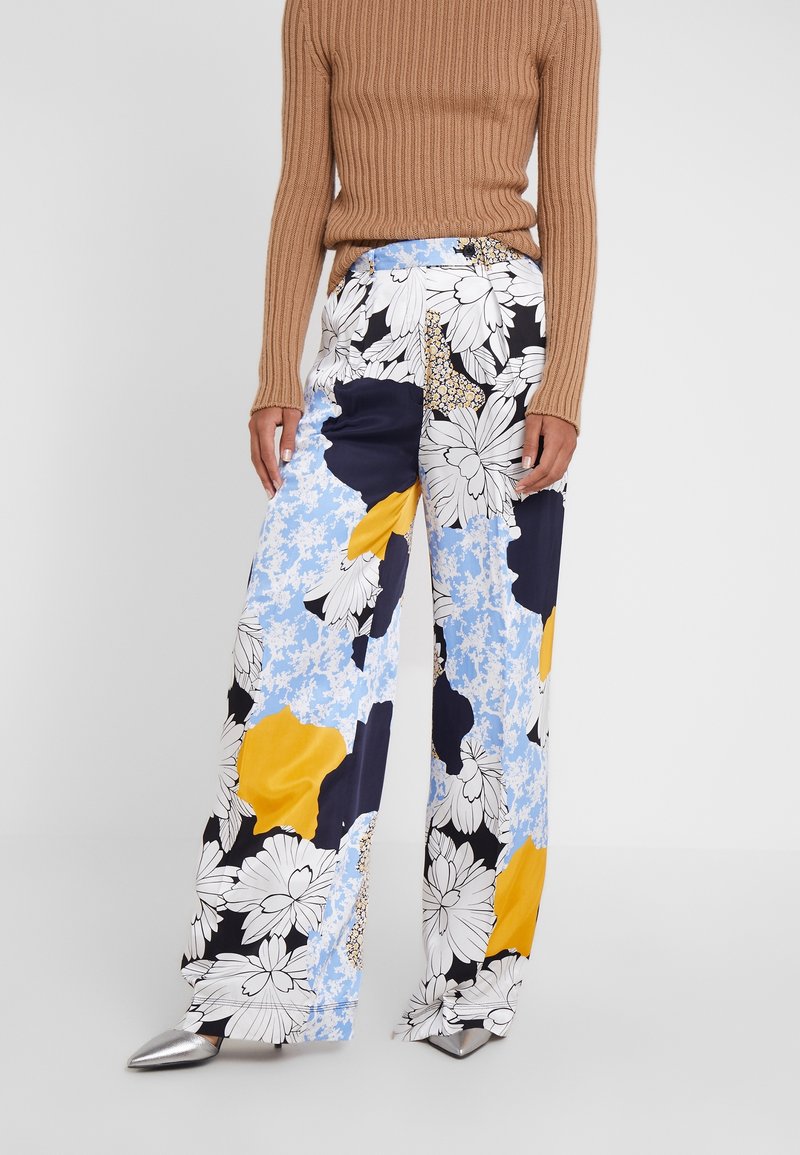Broek met een blauw, zwart en geel bloemenpatroon, gemaakt van lichtgewicht stof met een relaxte pasvorm en wijde benen, gecombineerd met een geribbelde bruine trui.