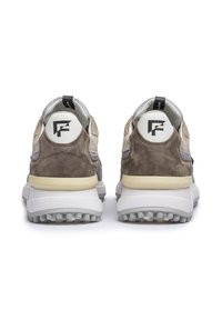 Zapatillas de ante marrón y gris con una suela blanca gruesa, forma redondeada y detalle del logo en el talón. Forro de textil suave y cuello acolchado.