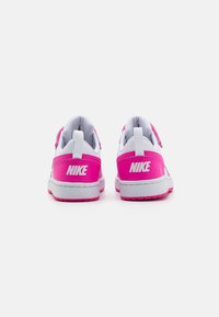 Nike-sneakers med en vit och stark rosa design, med en slät textilovandel, kardborreband och en strukturerad gummisula.