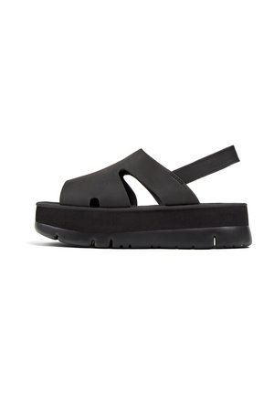 Black platform sandals made of smooth material with an open toe, cutout design, adjustable back strap, and textured sole for grip.