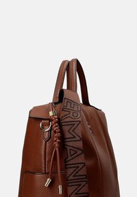 Borsa a mano in pelle marrone con superficie testurizzata, dotata di due manici superiori, un dettaglio intrecciato e una tracolla decorata con scritte.