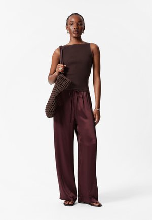 Brown ribbed sleeveless top, loose maroon satin pants with drawstring, and a woven brown bag. Smooth texture, simple design.
