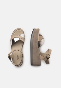 Beige platformové sandály s kovově stříbrným křížovým páskem a sponou na kotníku. Semišová textura na platformě a měkká stélka.