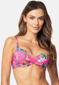Roze bikinitop met een bloemenpatroon met groene bladeren en witte orchideeën. Heeft verstelbare schouderbanden en een gedraaide voorkant.