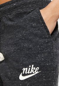 Grå idrottsshorts i texturerad tyg, med en sidficka och en vit Nike-logotyp på framsidan.