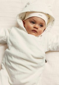Vit babydress med snödräkt och björonöron på huvan, med mjukt texturerat tyg och ett subtilt präglat björn mönster. Mjuk huvudband ingår.